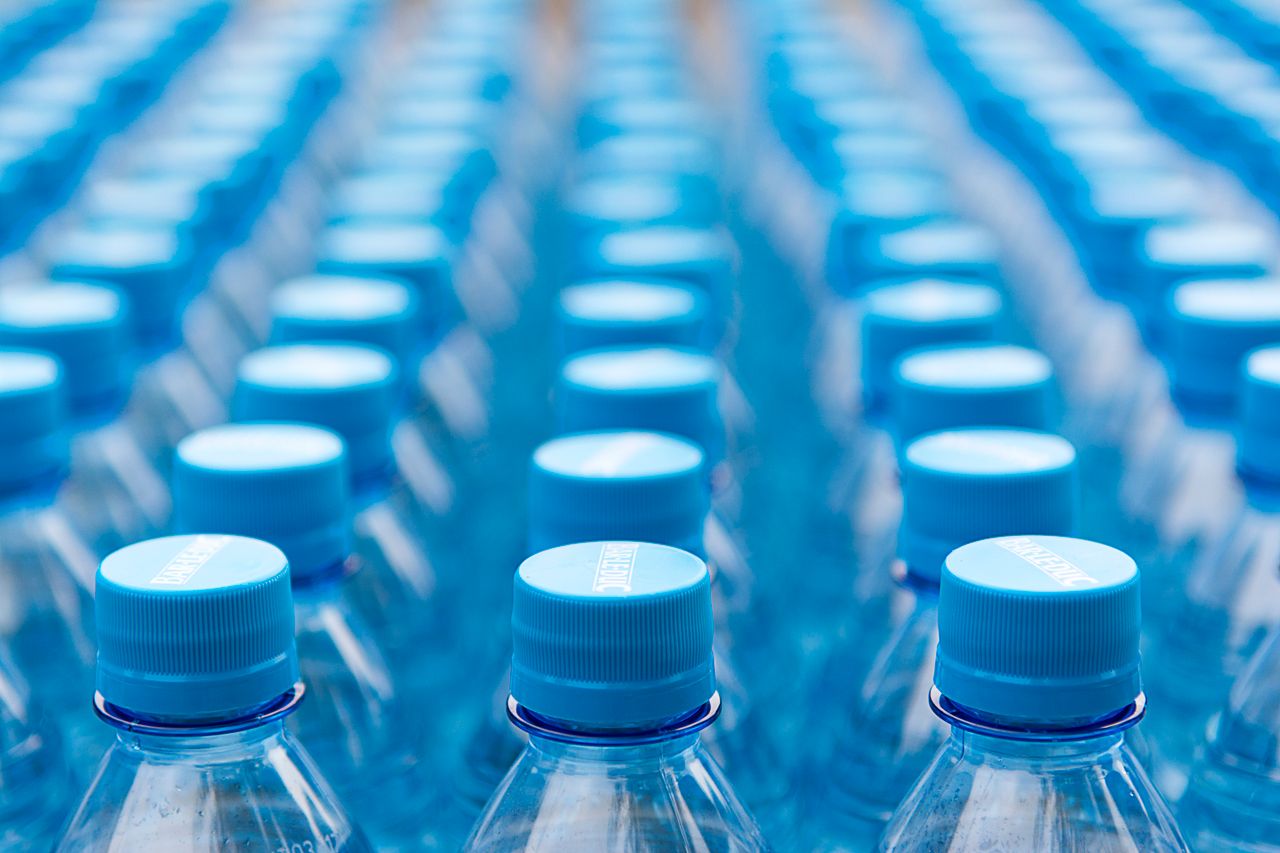 Array of blue plastic water bottles with caps arranged in a pattern. Ideal for recycling and packaging themes.